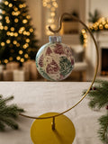Red and green tree toile napkin ornament on a gold stand