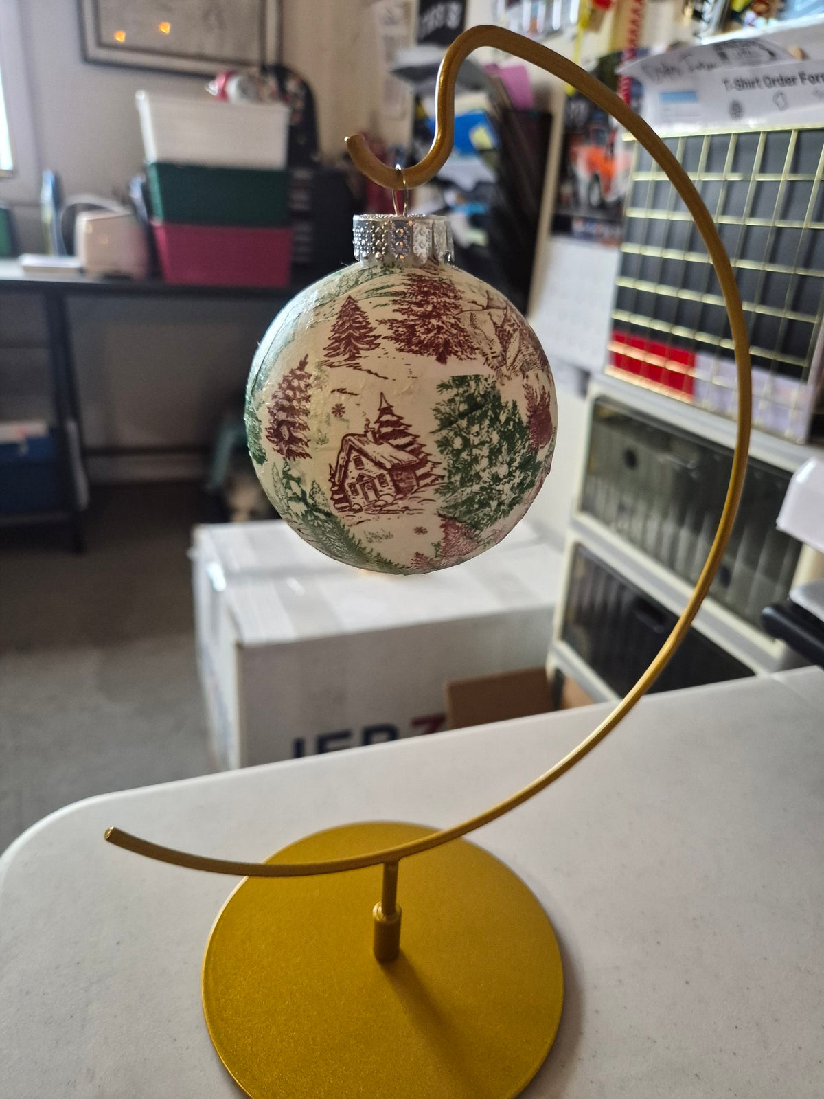 Real photo of the red and green tree toile ornament with a little cabin